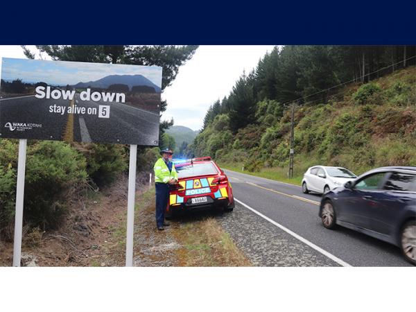 Senior Constable Steven Knox next to a road safety sign on the Napier-Taupo Road