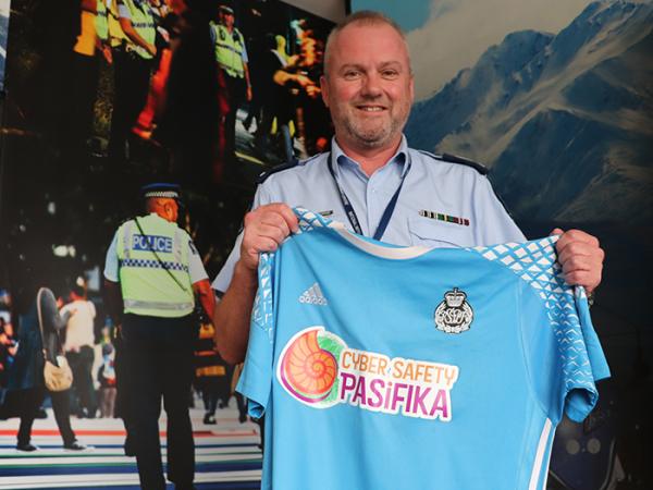 Senior Sergeant Mark Crawford holding up a football shirt