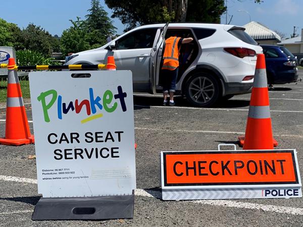 A Plunket car seat service sign and a Police checkpoint sign at the entrance to the clinic. 