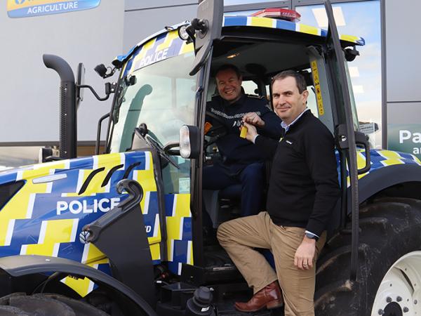 Assistant Commissioner for Iwi and Community Chris de Wattignar sitting in the Police tractor as Rod Gardner from Norwood hands 