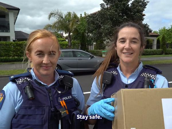 A screengrab from the video, showing two police officers holding a parcel in the street.