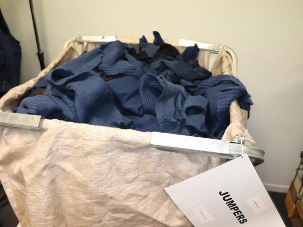 A container full of old Police jerseys that have been stripped of all non-woolleen parts.