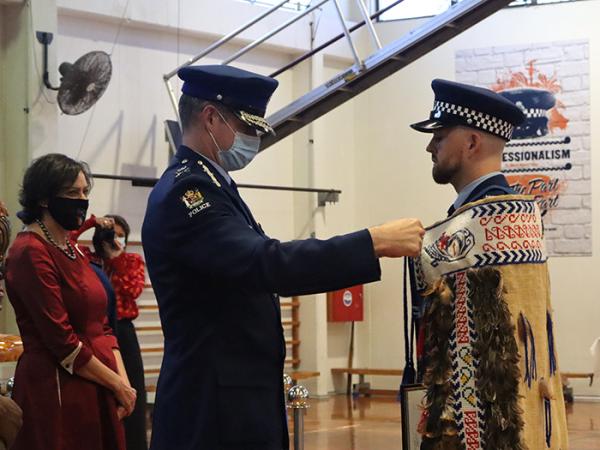 Commissioner Coster ties the korowai on Constable Lewis Ferguson.
