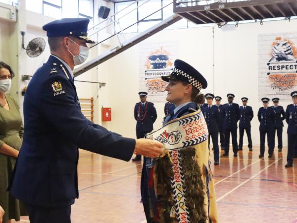 Commissioner Coster places the korowai around the shoulders of Constable Taylor Barker, top of the wing.