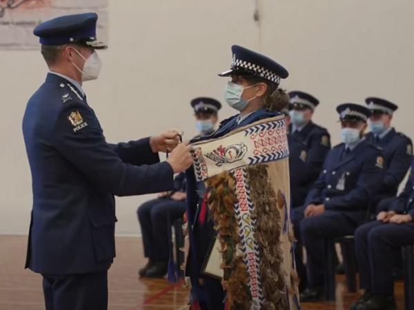 Commissioner Andrew Coster ties the korowai around the shoulders of Constable Summa Lewis, awarded first in wing.