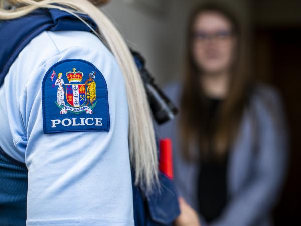 Image looking over the shoulder of a police officer as the talk to someone, who's not in focus.