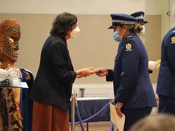 Police Minister Poto Williams handing one of the graduates her ID card.
