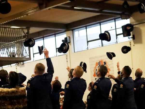 Photo taken from behind the graduates as they throw their hats into the air at the end of the graduation ceremony. 