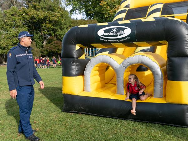 An officer talking to a young pupil as they finish the obstacle course. 