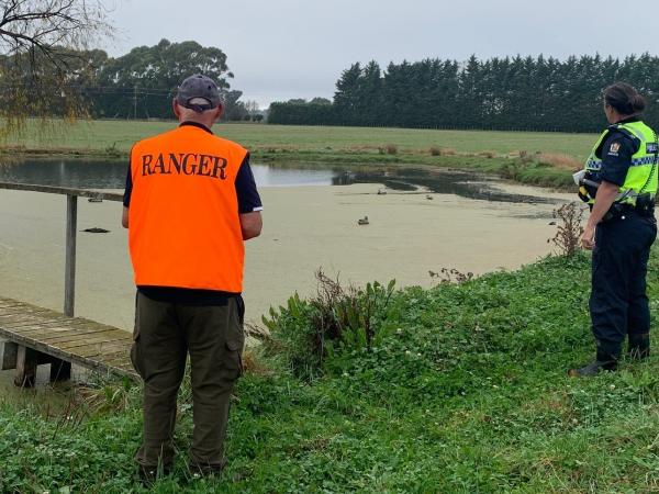 Police officer and Fish and Game Ranger looking over the duck pond.