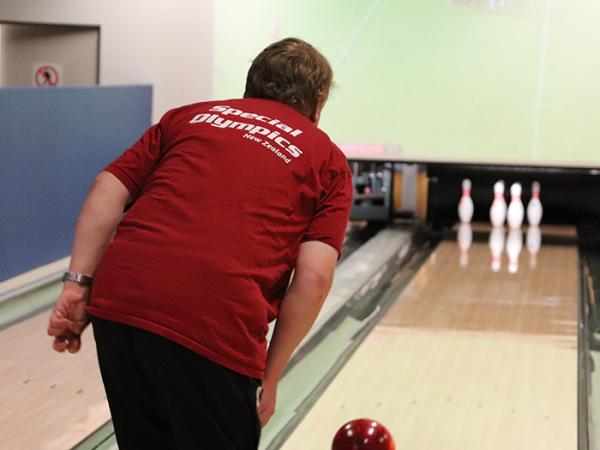 Shot from behind of one of the athletes bowling.