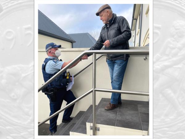 An officer shaking hands with Dennis Owen, who received the medal on behalf of the family. 