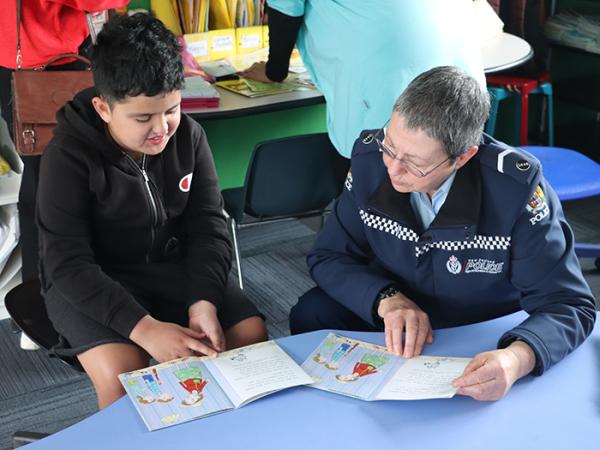 Senior Constable Tess Brownlie connects through reading with Te Wharau School student Jayden.