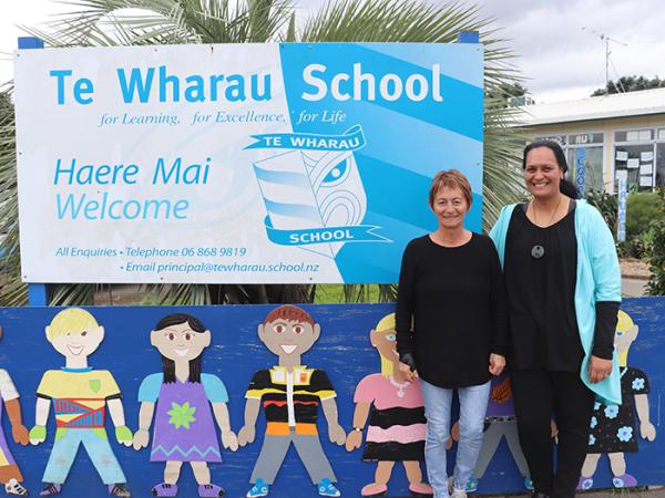 Margie Ricards, left, and Jonette Rudge standing next to the school's sign.