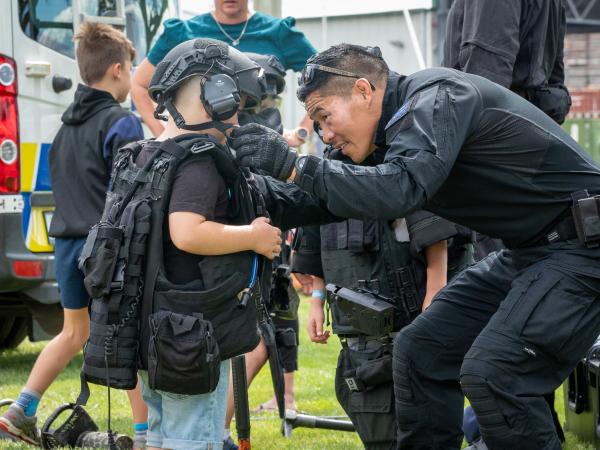 Sergeant Willie Tran helps a child try on the AOS gear for size.