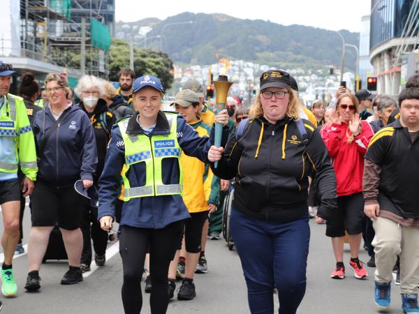 Officer and athlete holding the torch and leading the parade down Bowen Street.