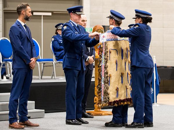 Police Commissioner Andrew Coster ties the Police korowai on to the First in Wing Constable Emma Hensman...