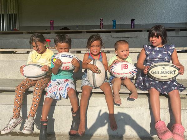 Five children holding rugby balls given to them to keep. 