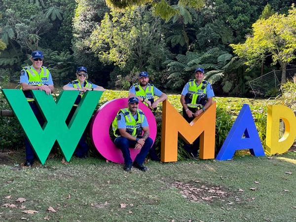 Taranaki Police staff next to the WOMAD sign.