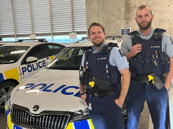 Constables Travis Smith and Connor Spiers standing next to a police car. 