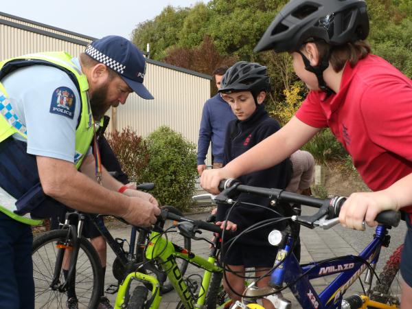 Senior Constable Ken Terry helps fit the bike lights for students at Leithfield School. 
