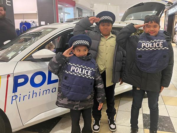 Kids dressed up in Police vests by a police car inside the mall. 