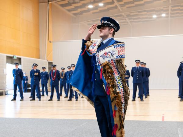 First in Wing Constable Alexander Kerr saluting while wearing the RNZPC korowai.