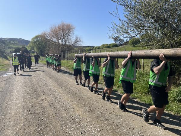 Participants carrying logs along a road. 