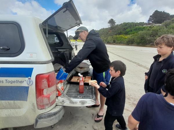 BBQ sausages being served from the back of the police cruiser.