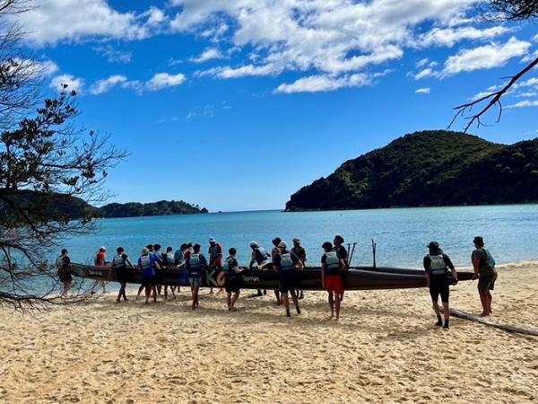 Some of the group carrying a waka across the sand to the beach. 