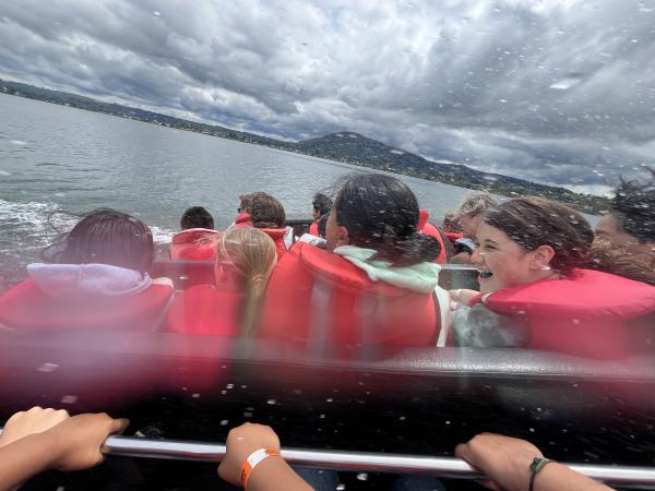 Some of the children laughing on the jet boat as water sprays everywhere.
