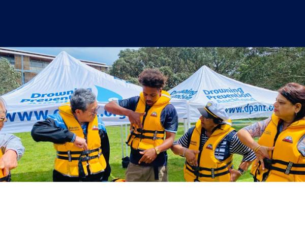 A group of people trying on lifejackets and getting to grips with how to wear them correctly. 