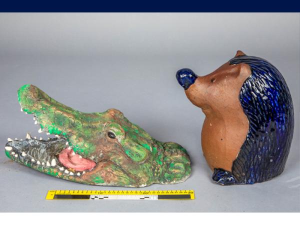 Two garden ornaments - a crocodile head and a painted pottery hedgehog.