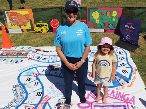 Senior Constable Rosie Marchant and a young fan of her 'Help Glo Bro Home' road safety board game.