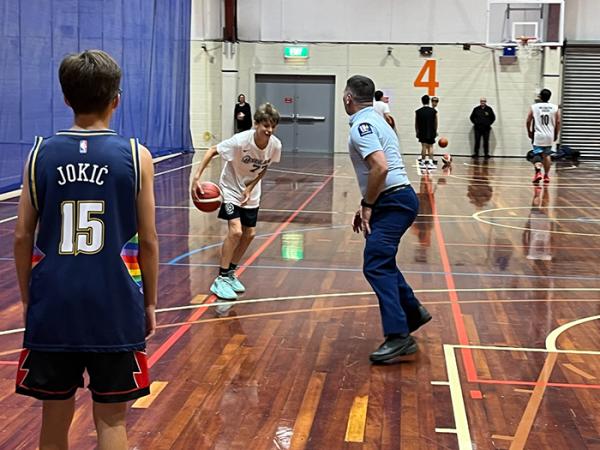 A young player about to dribble the ball past Senior Constable Paul Bascand.