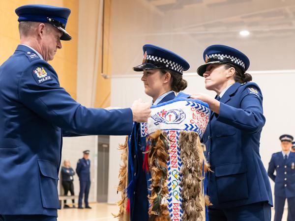 Commissioner Andrew Coster tying the Police korowai around the shoulders of First in Wing Constable Alexandra Wilson.