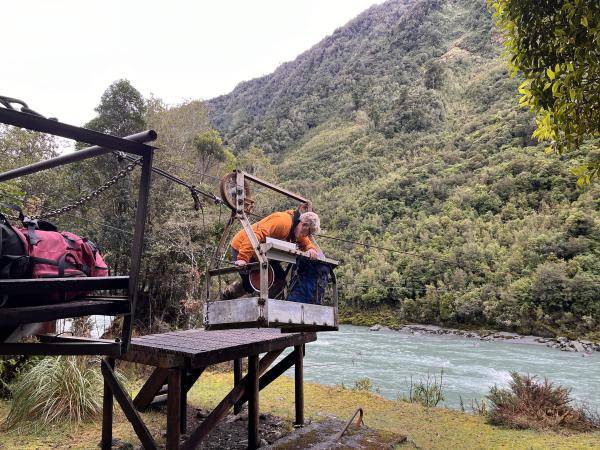 Searchers transport themselves and equipment across the swollen river.