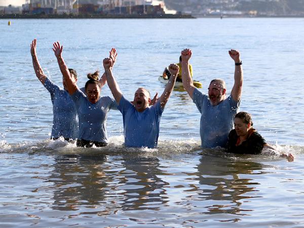 Officers in the sea with their arms raised in celebration during the Polar Plunge.