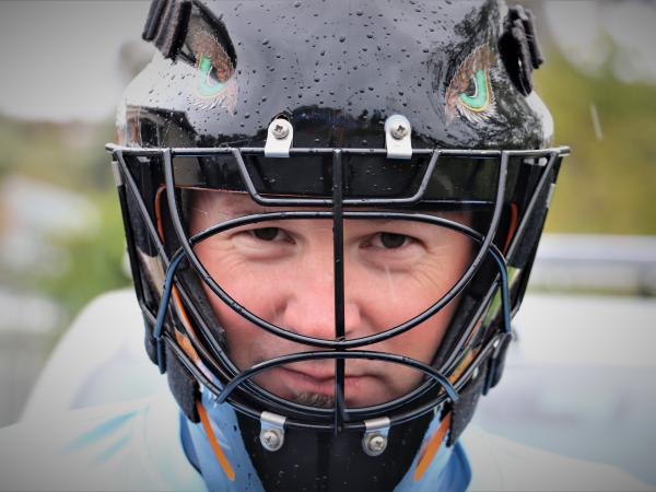 A close up of Constable Sam Davidson's face wearing the protective head gear that's part of his New Zealand hockey kit.