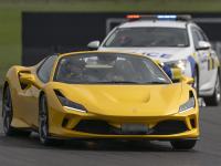 A yellow Ferrari on the racetrack with a police car following behind. 
